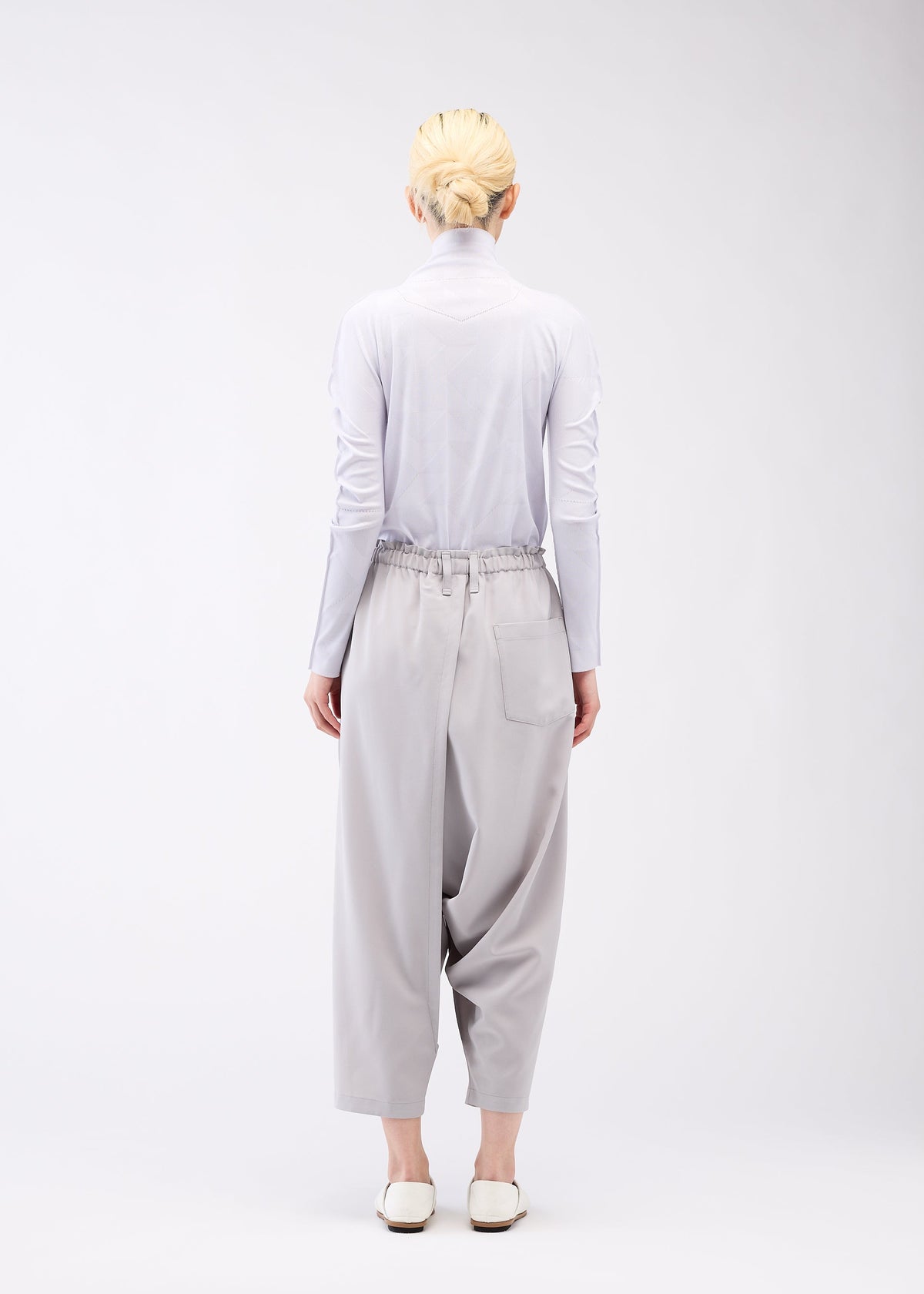 A model wears the 132 5. ISSEY MIYAKE SEAMLESS 1 trousers.