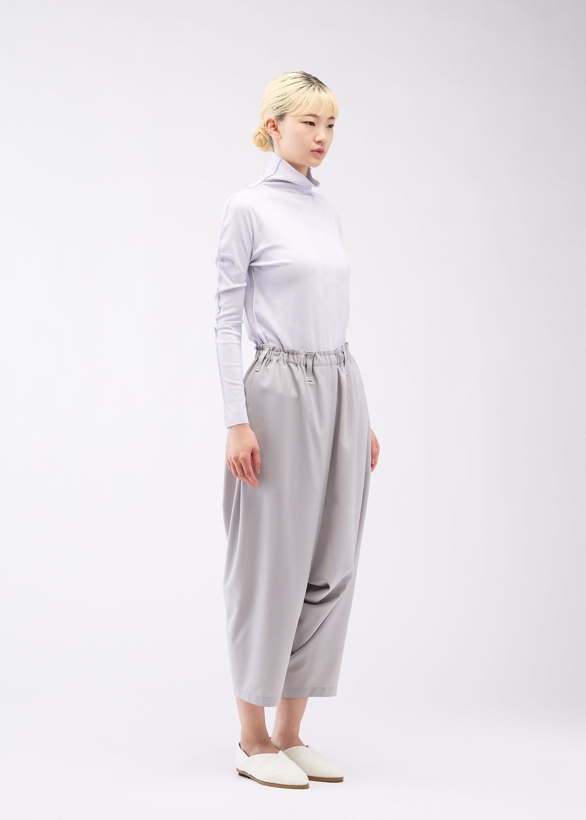 A model wears the 132 5. ISSEY MIYAKE SEAMLESS 1 trousers.