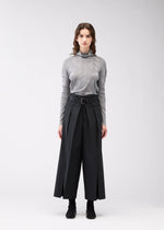 A model wears the 132 5. ISSEY MIYAKE FLAT SIDE FOLD trousers.
