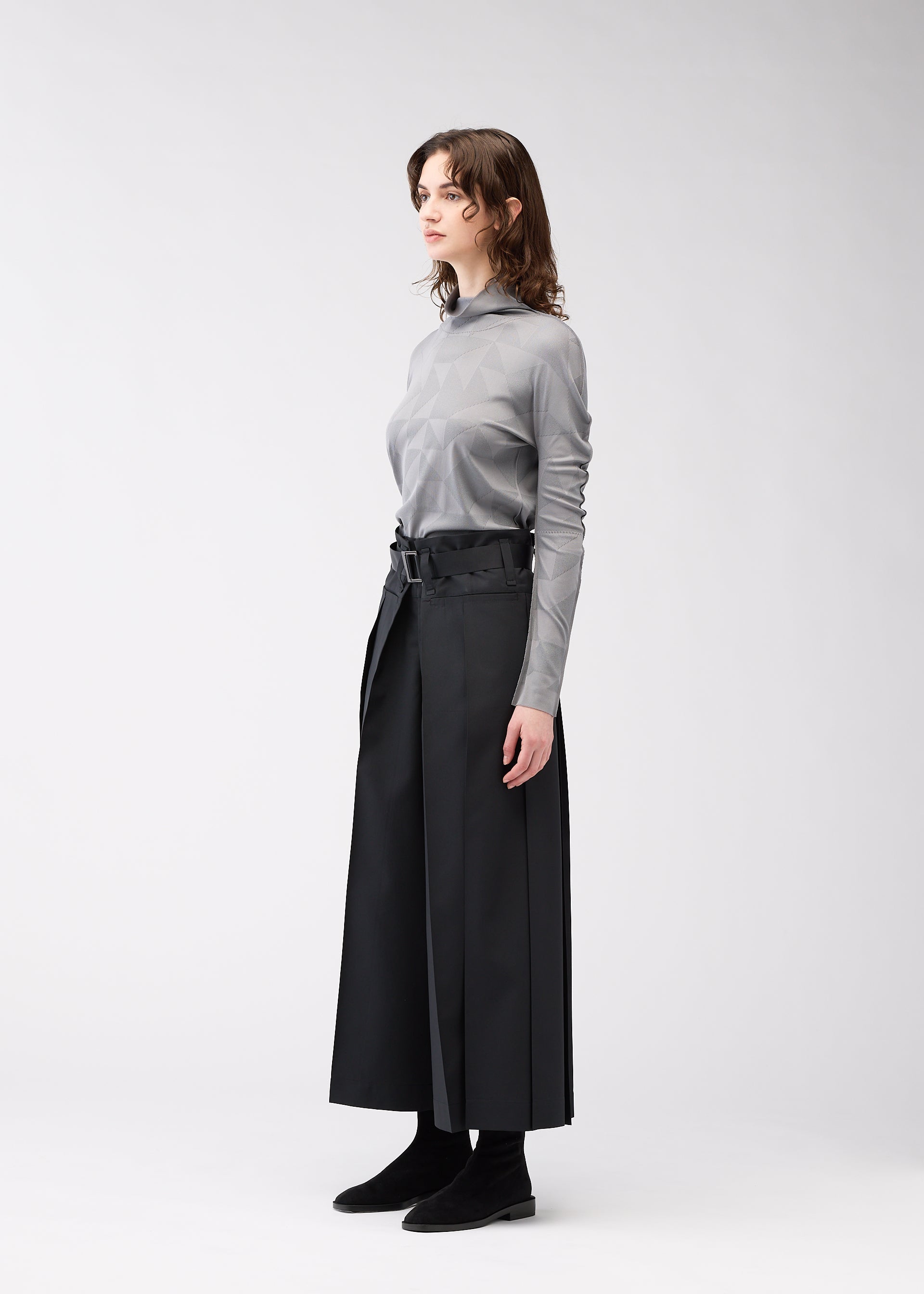 A model wears the 132 5. ISSEY MIYAKE FLAT SIDE FOLD trousers.