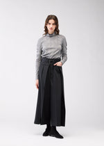 A model wears the 132 5. ISSEY MIYAKE FLAT SIDE FOLD trousers.