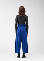 A model wears the 132 5. ISSEY MIYAKE WOOL LIKE FLAT TUCK trousers.