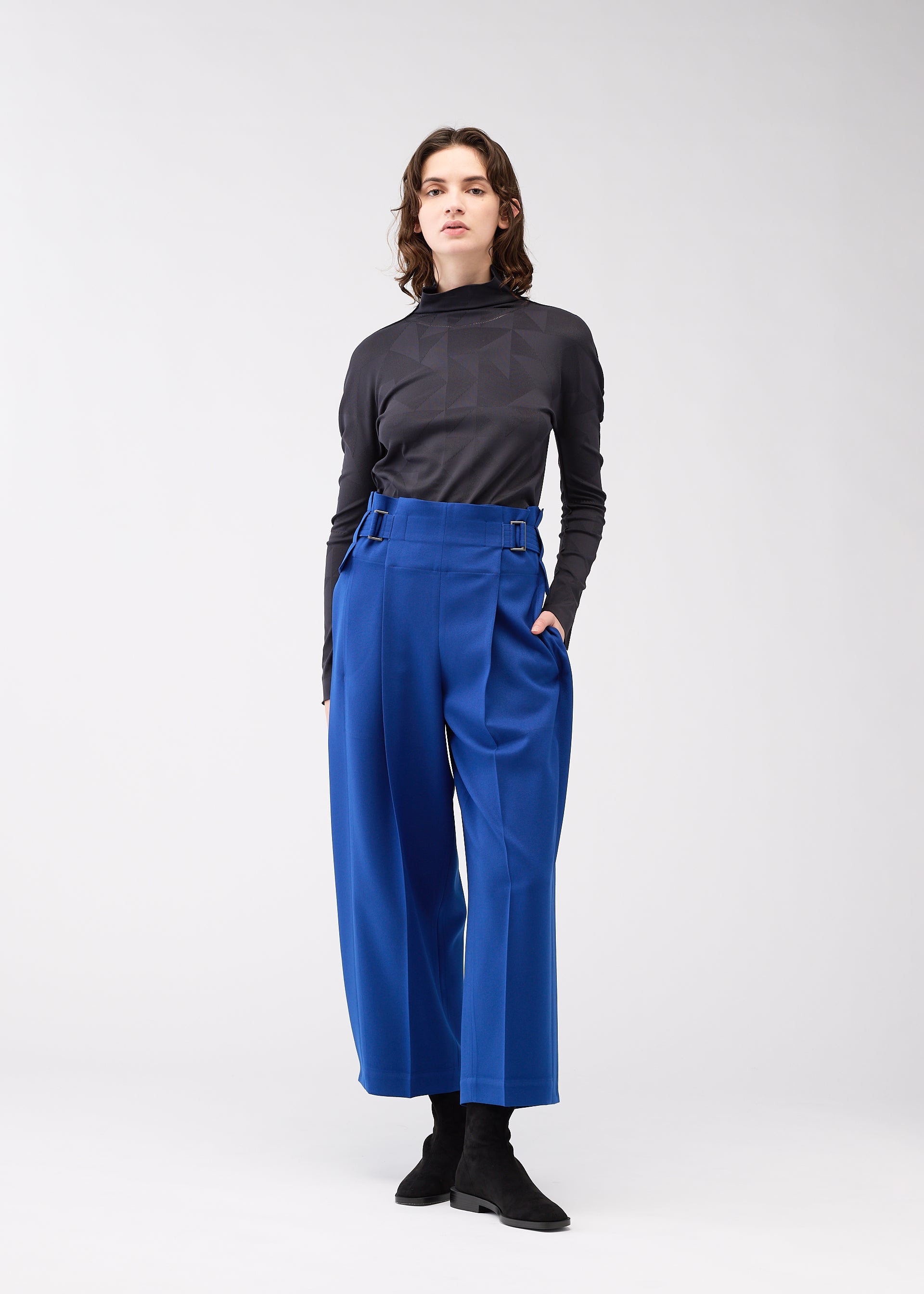 A model wears the 132 5. ISSEY MIYAKE WOOL LIKE FLAT TUCK trousers.