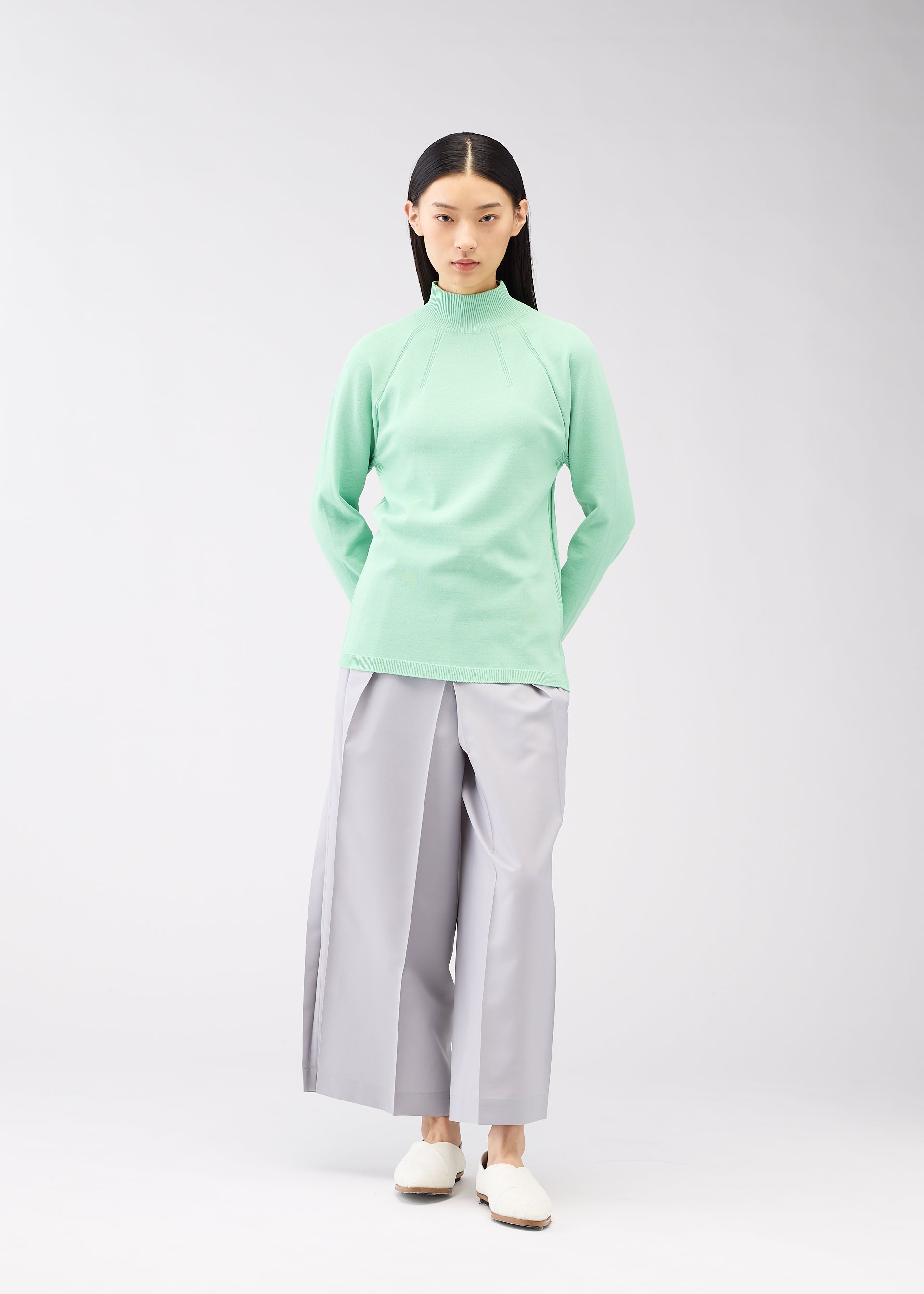 A model wears the 132 5. ISSEY MIYAKE DARTED KNIT top.