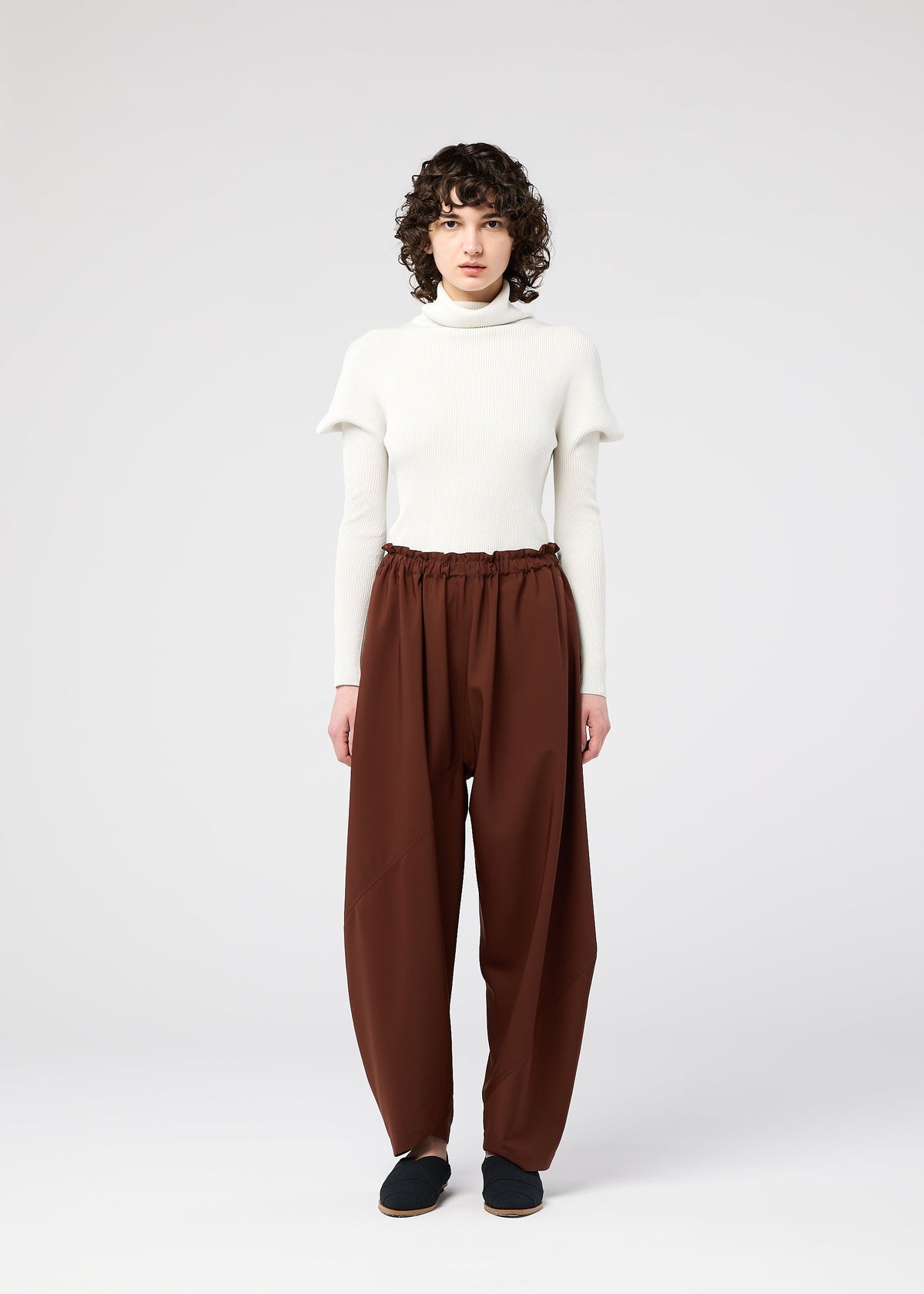 A model wears the 132 5. ISSEY MIYAKE PARALLEL WRAP trousers.