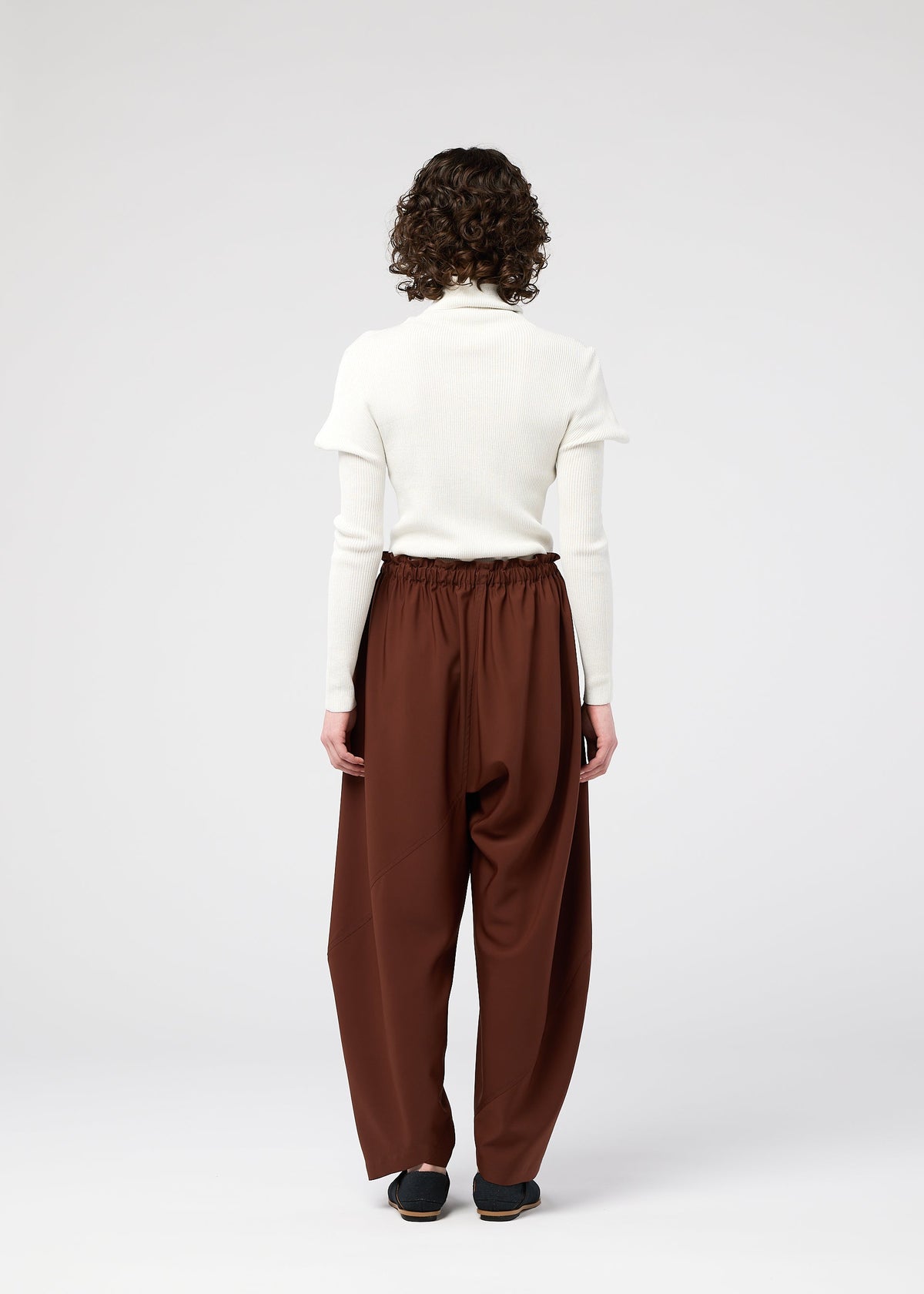 A model wears the 132 5. ISSEY MIYAKE PARALLEL WRAP trousers.
