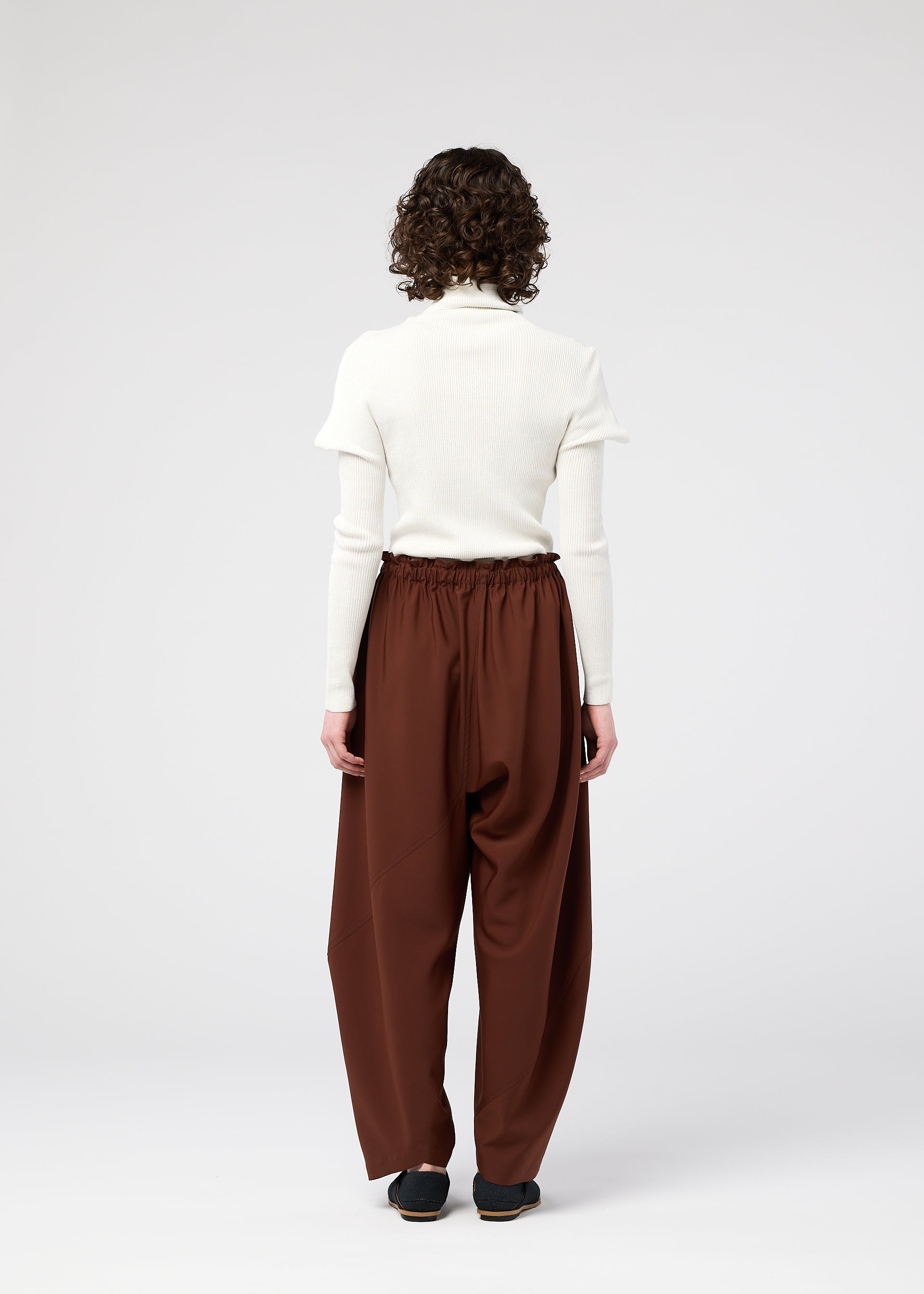 A model wears the 132 5. ISSEY MIYAKE PARALLEL WRAP trousers.