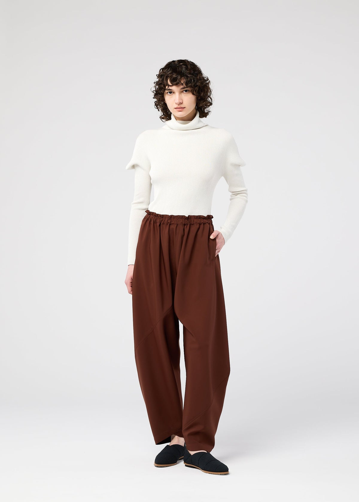 A model wears the 132 5. ISSEY MIYAKE PARALLEL WRAP trousers.