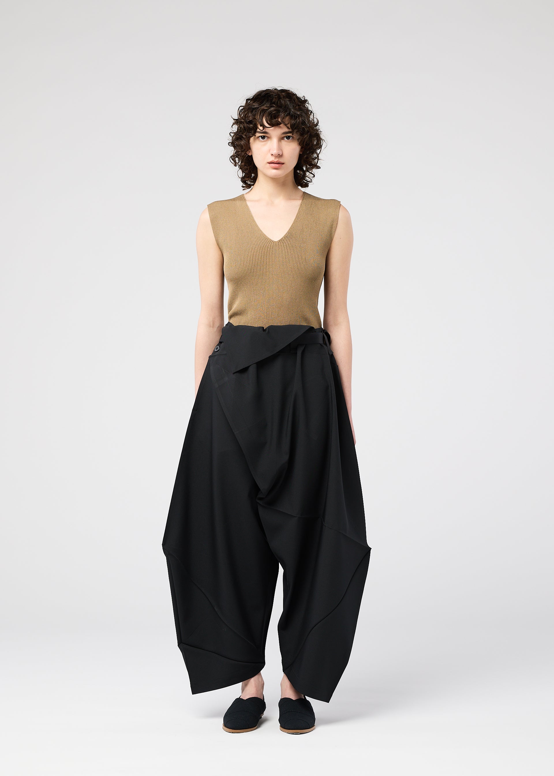 A model wears the 132 5. ISSEY MIYAKE FACET SOLID trousers.