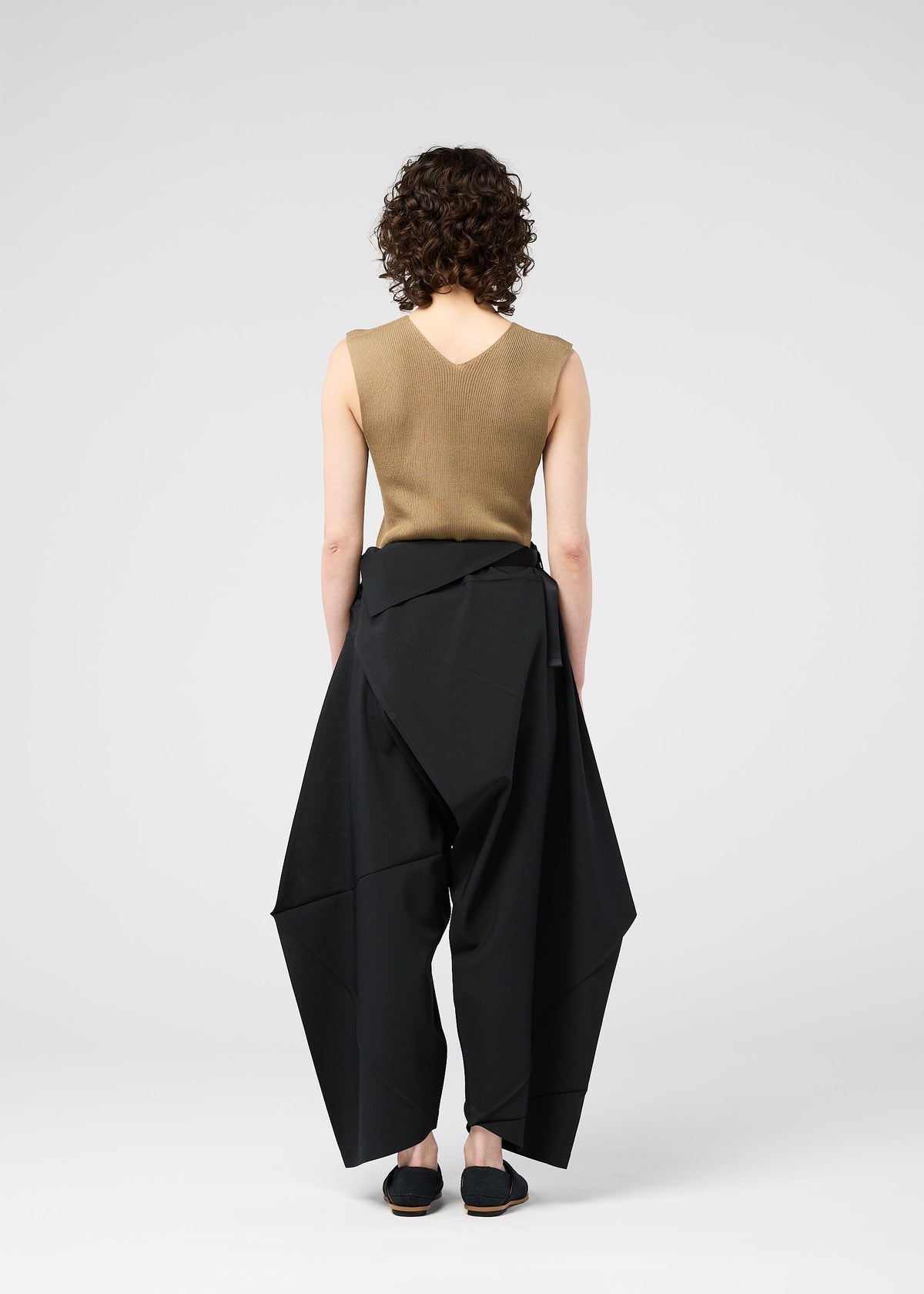 A model wears the 132 5. ISSEY MIYAKE FACET SOLID trousers.