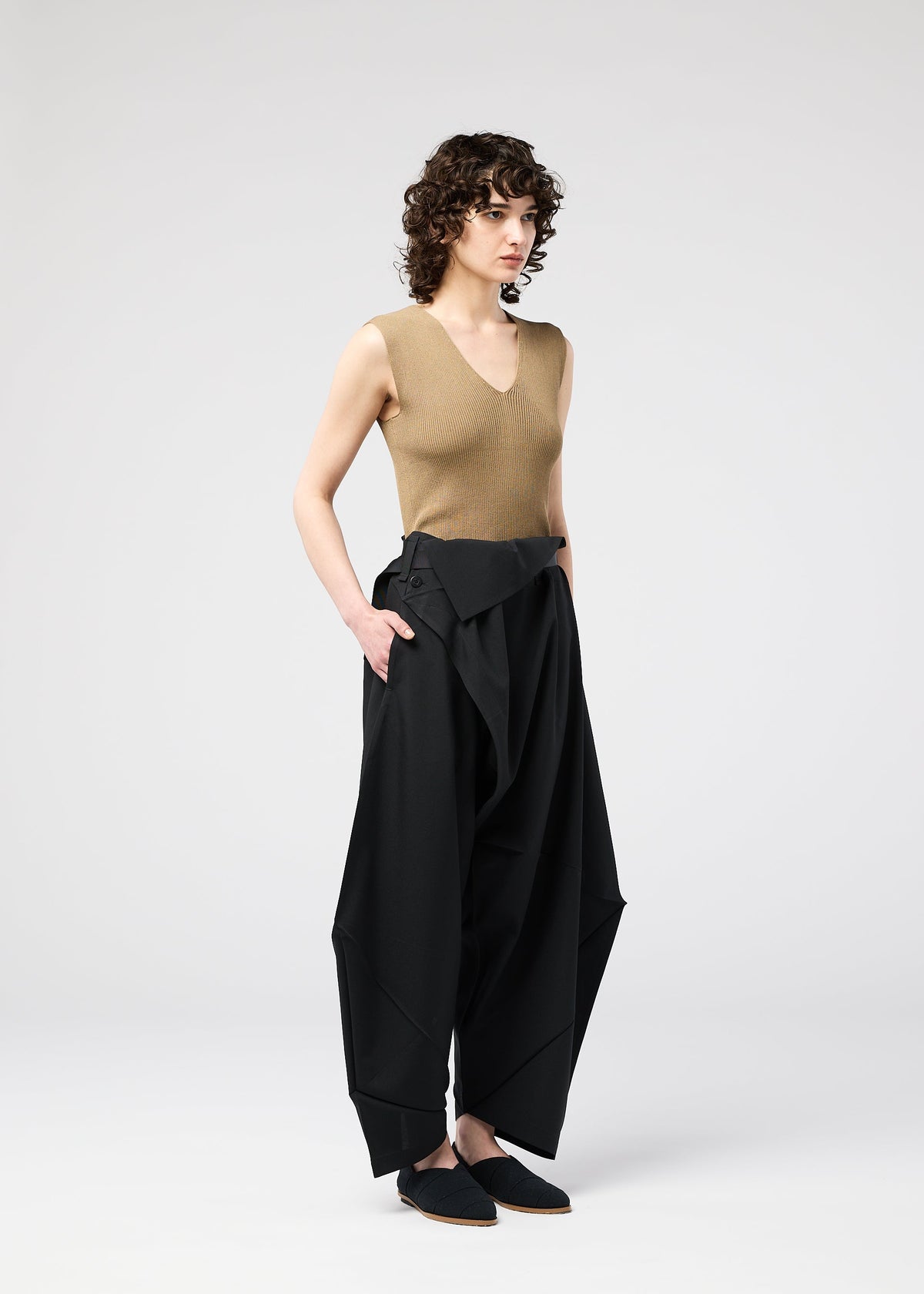 A model wears the 132 5. ISSEY MIYAKE FACET SOLID trousers.