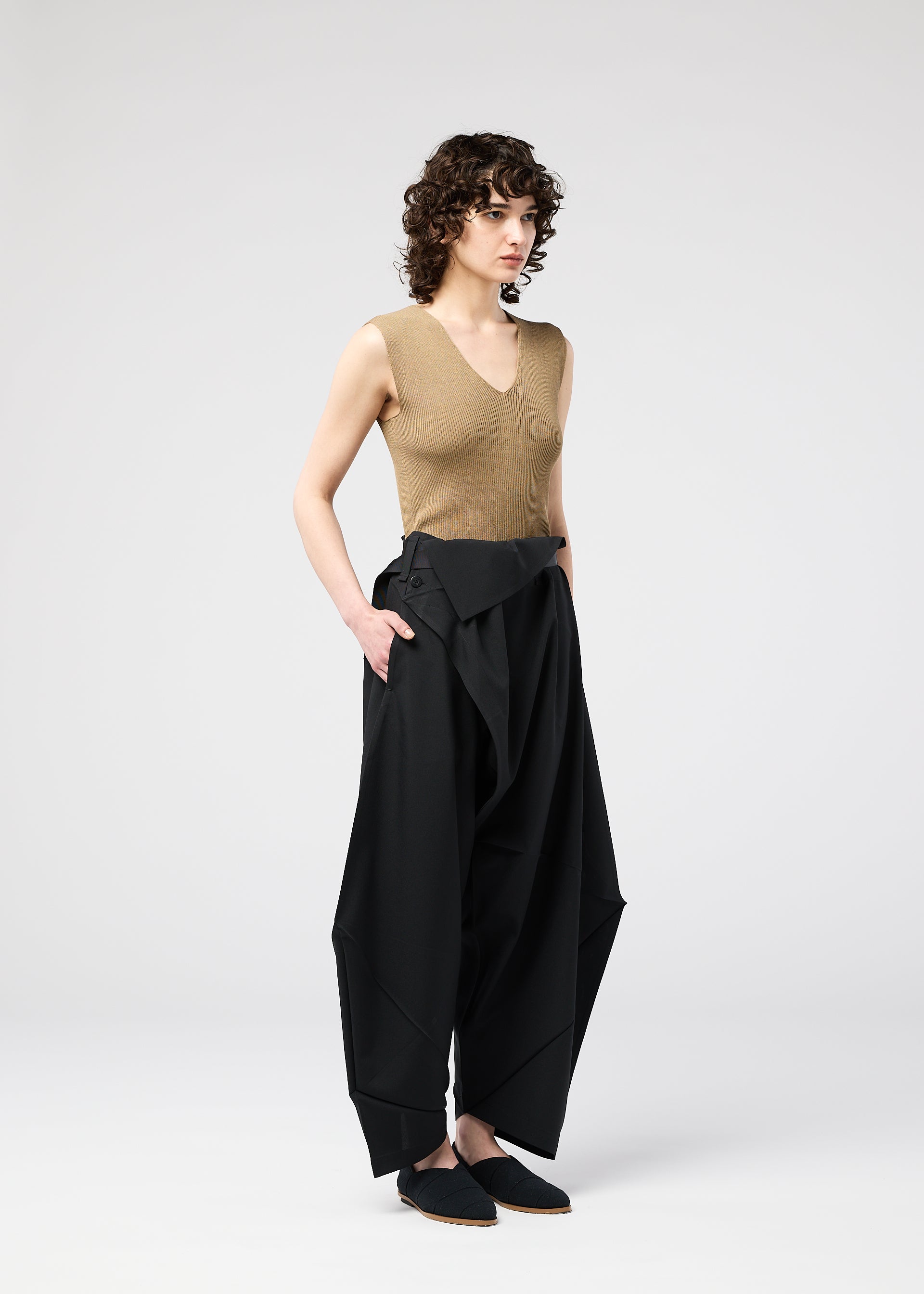 A model wears the 132 5. ISSEY MIYAKE FACET SOLID trousers.