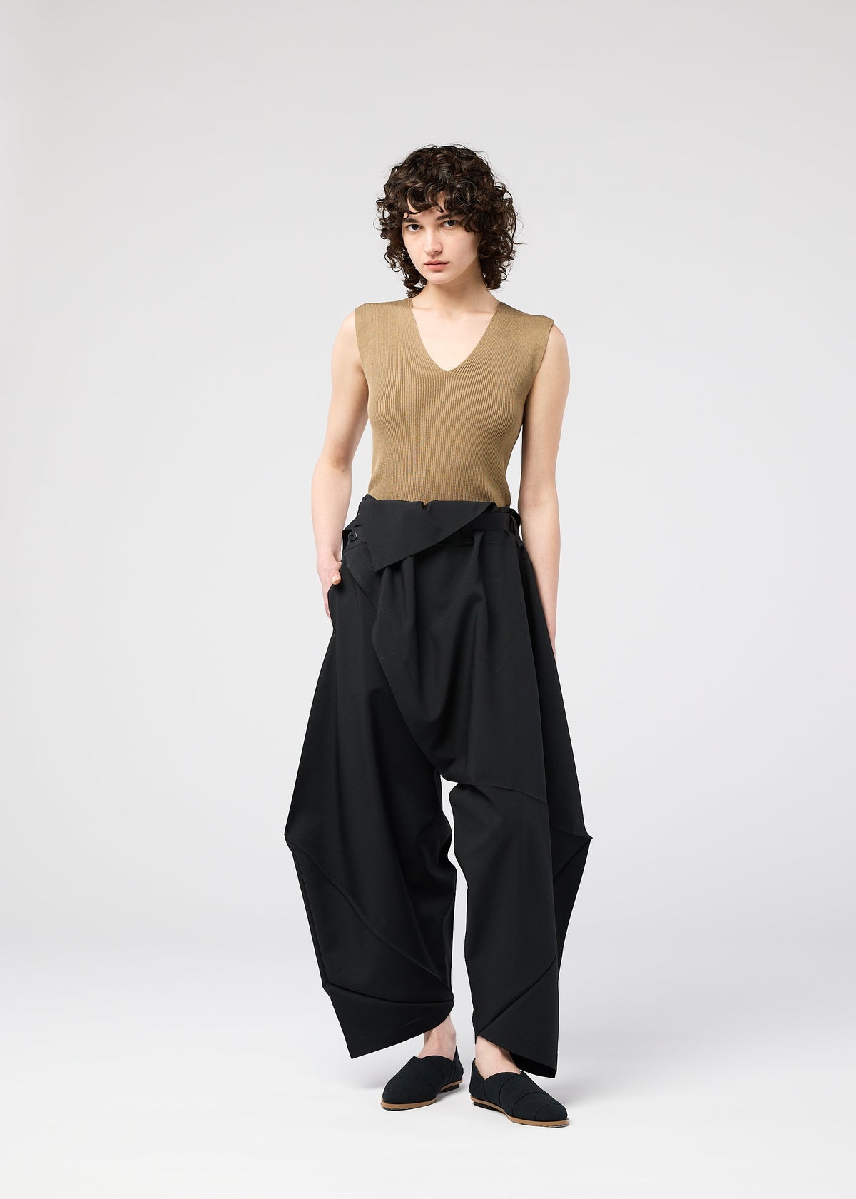 A model wears the 132 5. ISSEY MIYAKE FACET SOLID trousers.