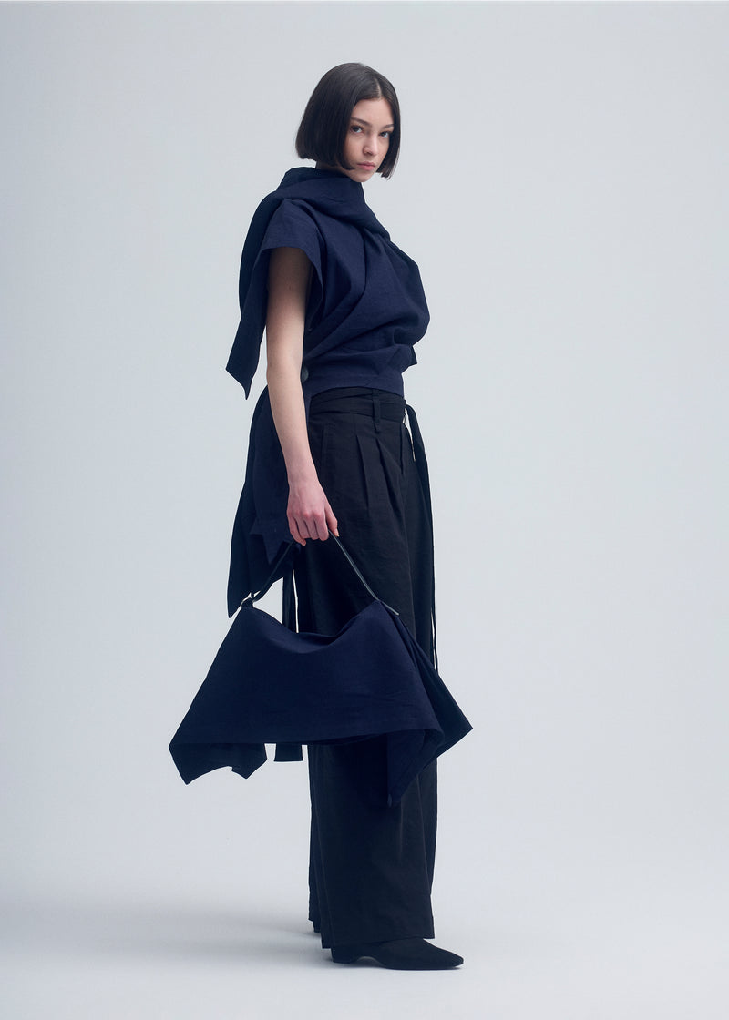 A model wears the ISSEY MIYAKE  ENCLOTHE SQUARE bag