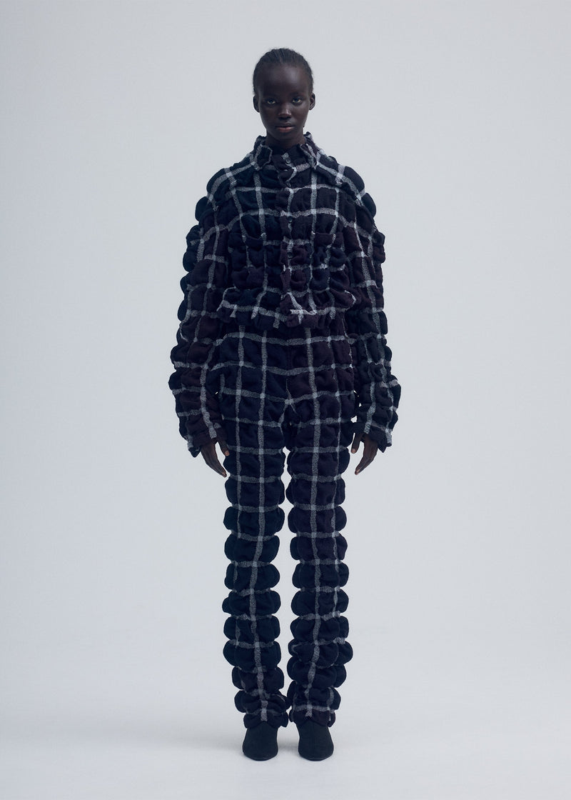 A model wears the ISSEY MIYAKE PRISM CHECK jacket.