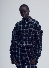 A model wears the ISSEY MIYAKE PRISM CHECK jacket.