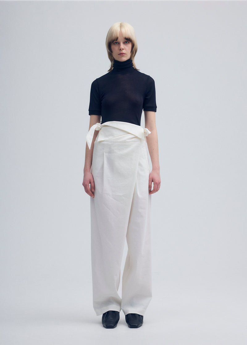 A model wears the ISSEY MIYAKE  ENCLOTHE PANTS trousers