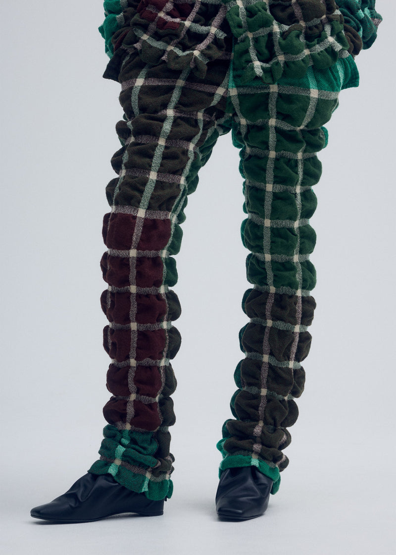 A model wears the ISSEY MIYAKE PRISM CHECK trousers.