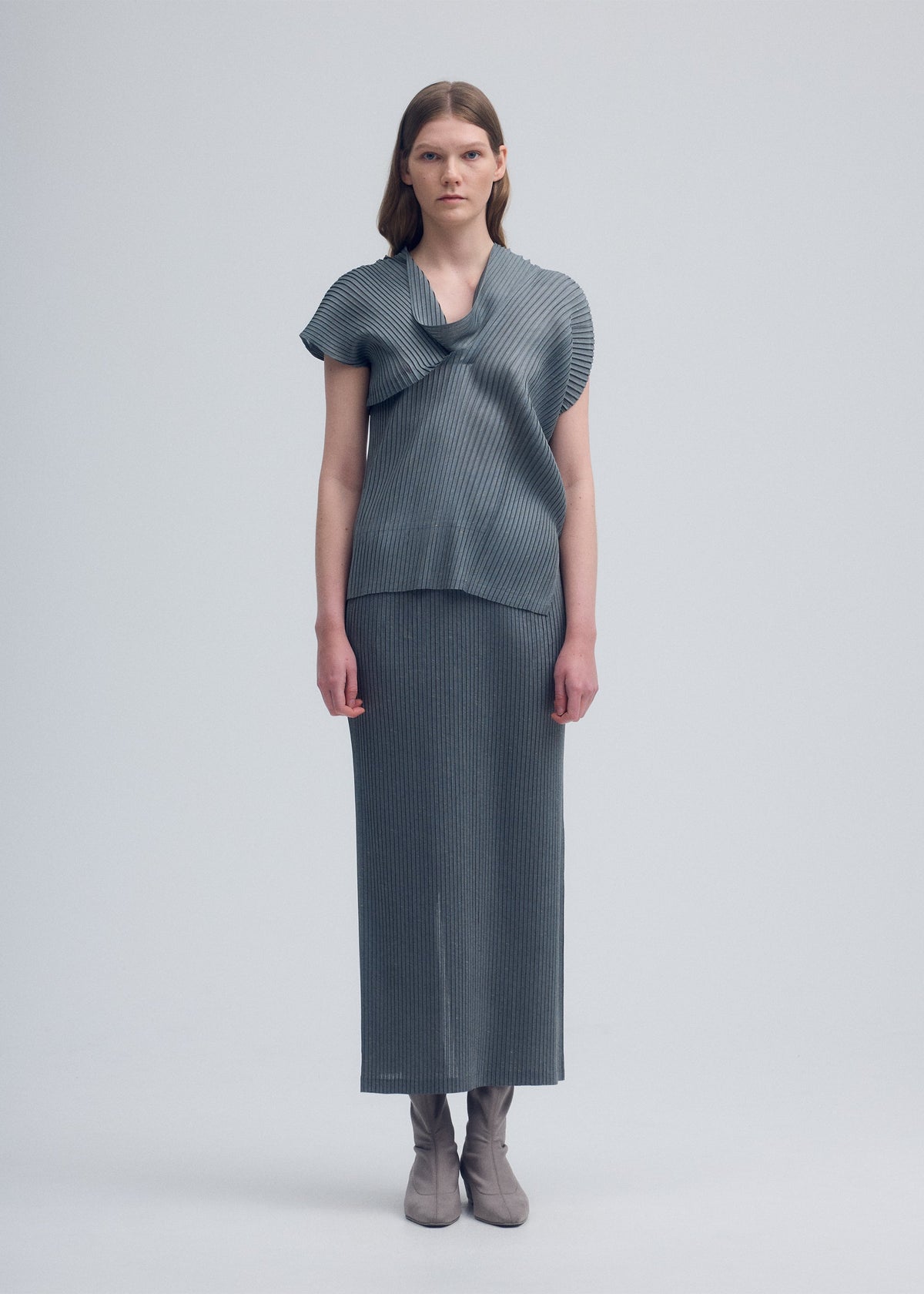 A model wears the ISSEY MIYAKE RESTORE BLEND PLEATS skirt.