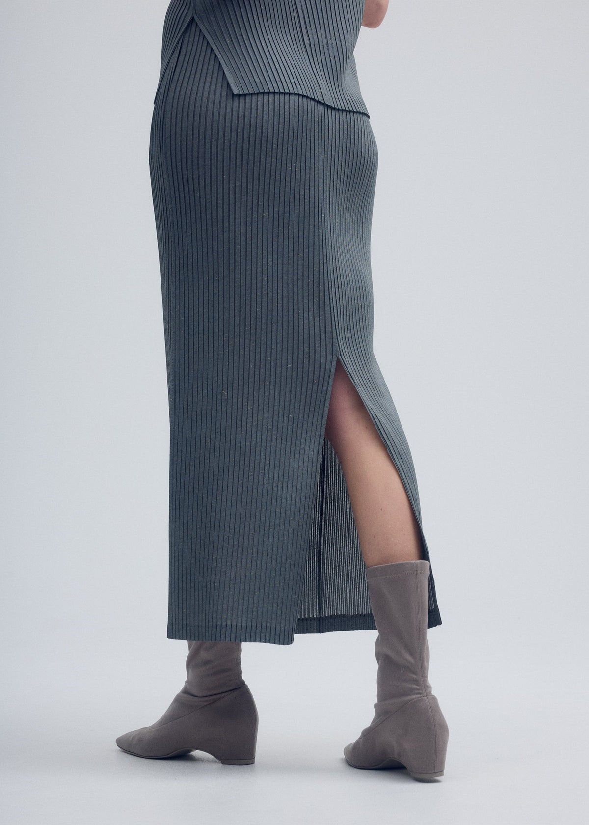 A model wears the ISSEY MIYAKE RESTORE BLEND PLEATS skirt.