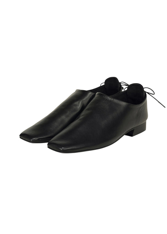 A product shot of the ISSEY MIYAKE AROUND THE HEEL shoes in black (15).