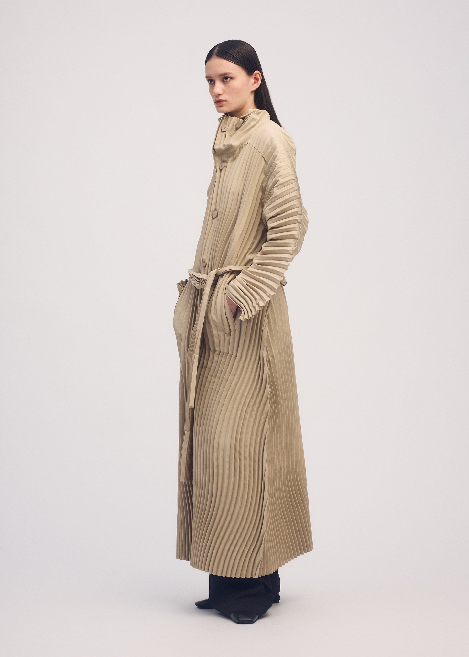 A model wears the ISSEY MIYAKE WAVERING PLEATS coat.