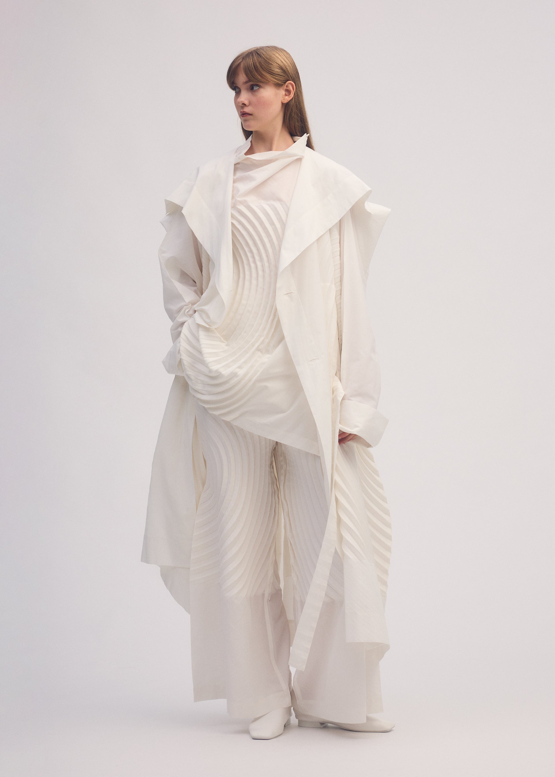 A model wears the ISSEY MIYAKE FLOW coat.