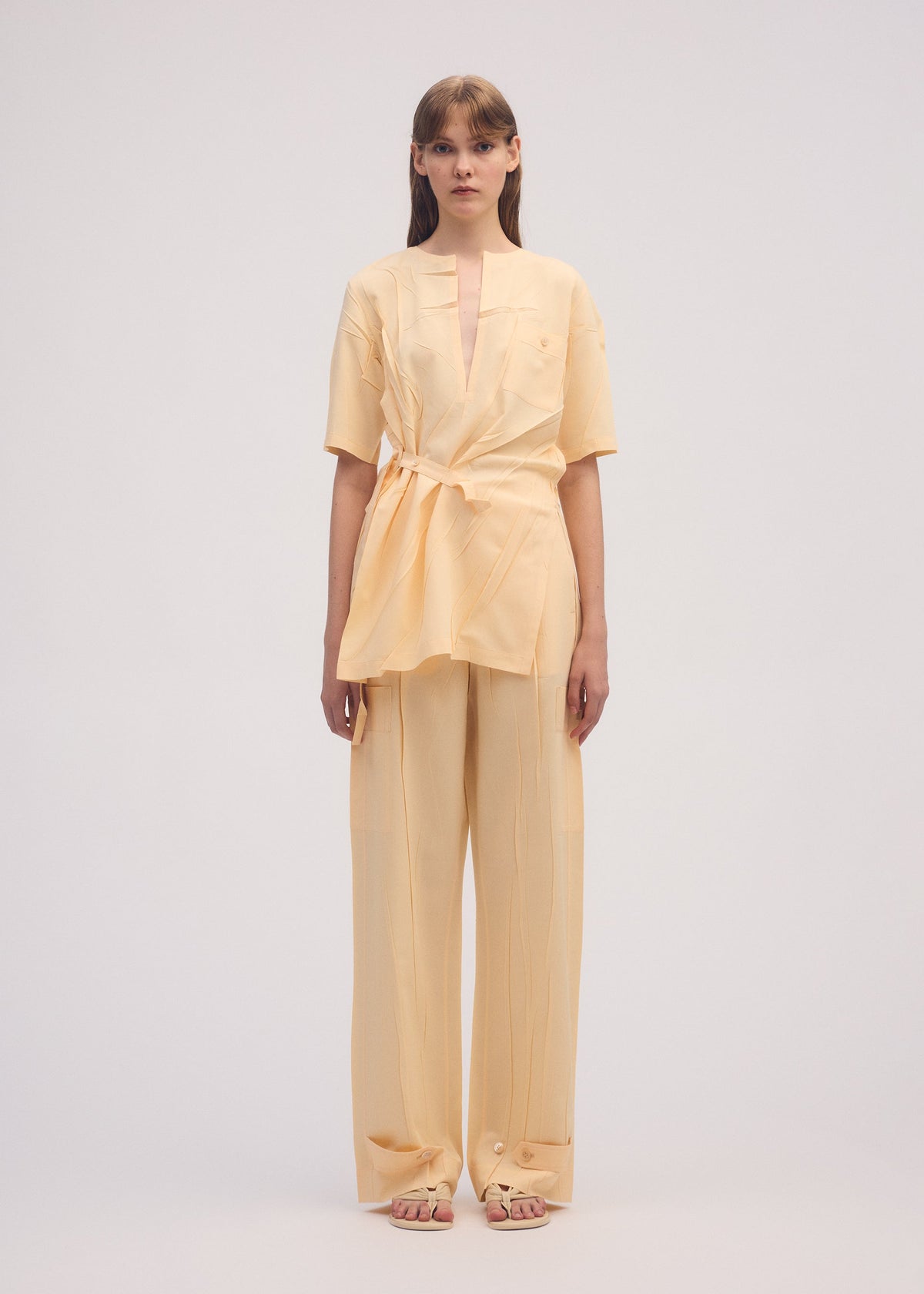 A model wears the ISSEY MIYAKE PRESSED FORM trousers.