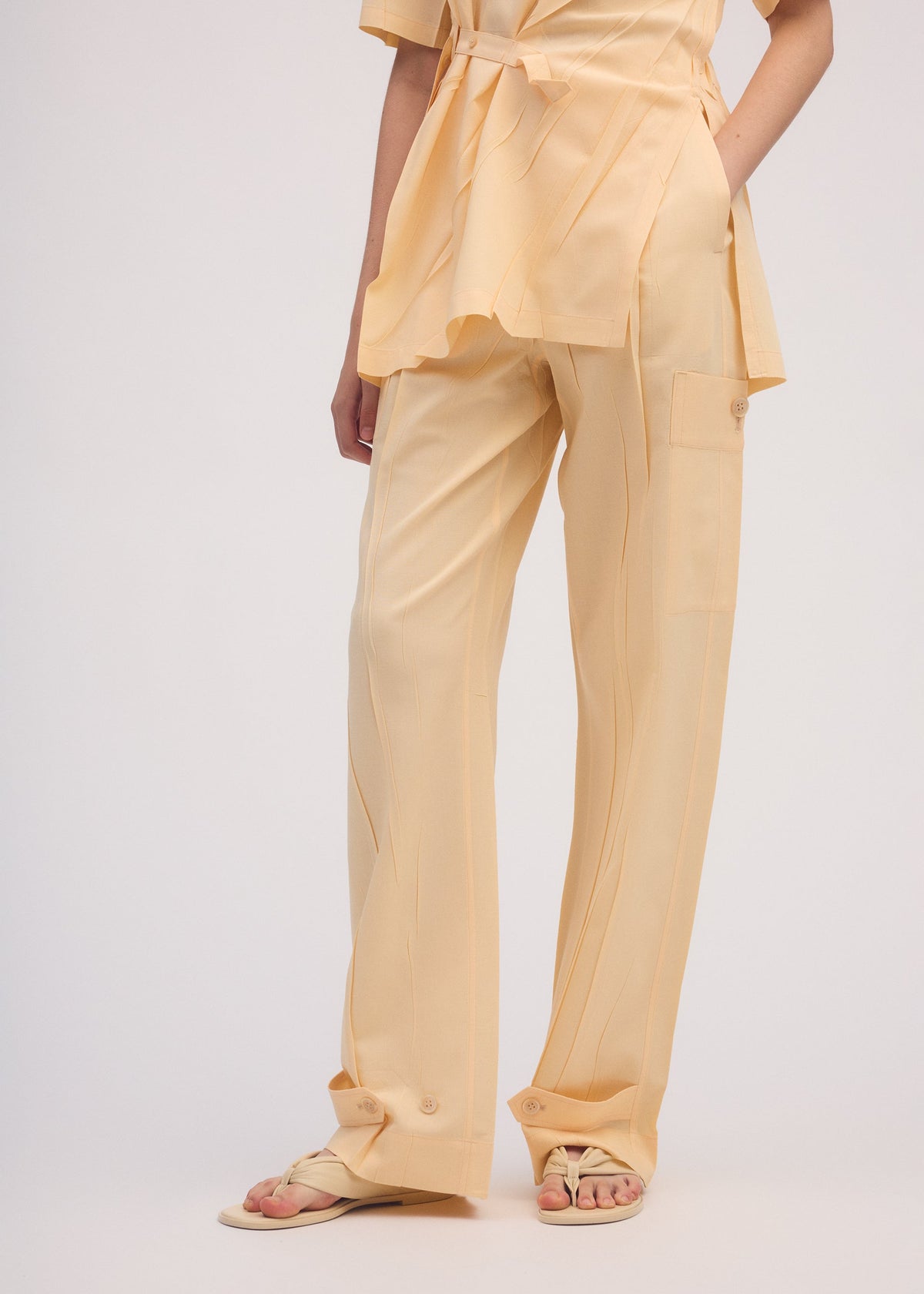A model wears the ISSEY MIYAKE PRESSED FORM trousers.