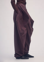 A model wears the ISSEY MIYAKE PERSONALITY PANTS trousers.