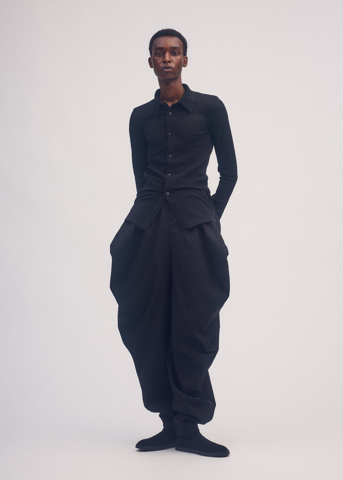 A model wears the ISSEY MIYAKE PERSONALITY PANTS trousers.