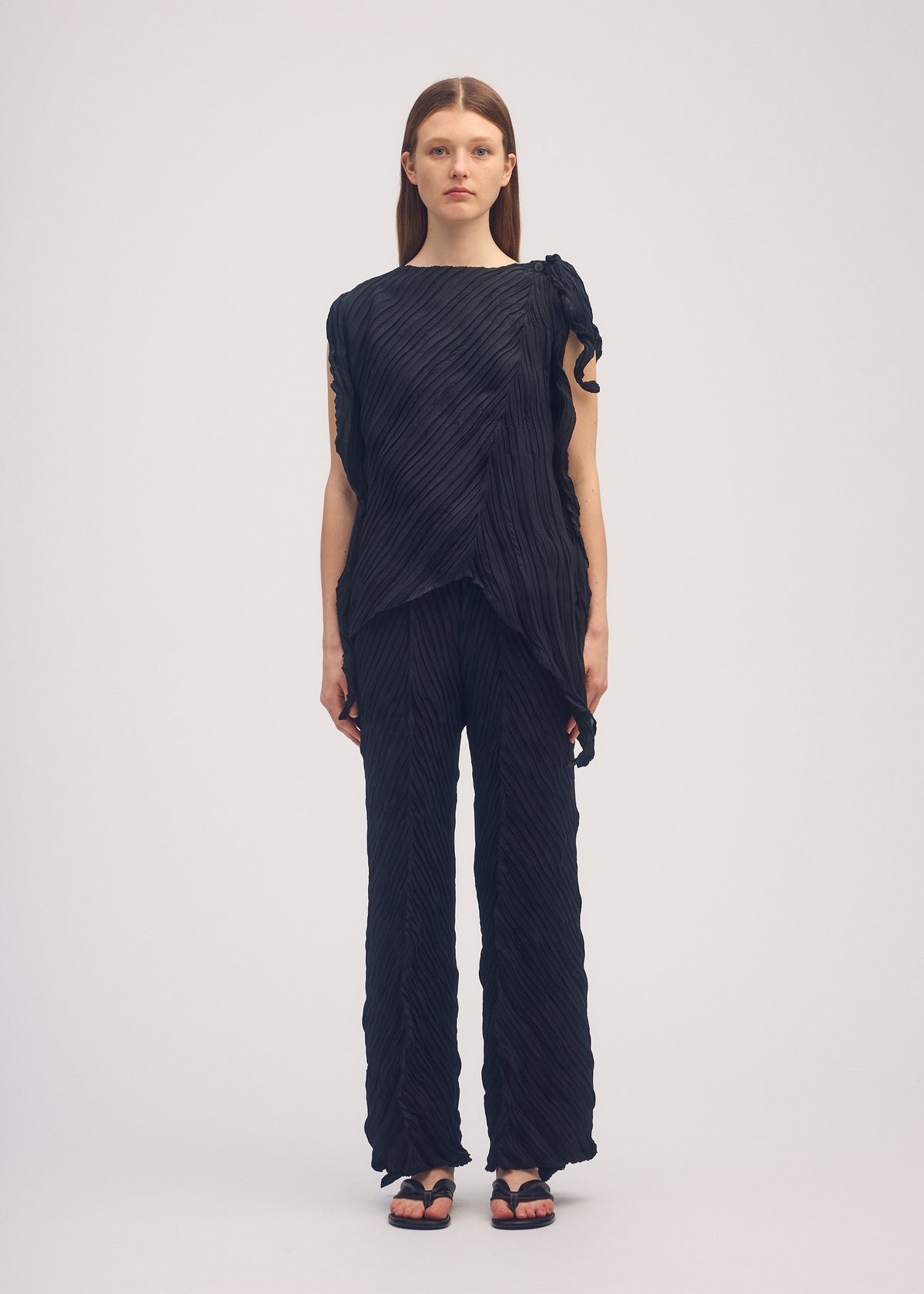 A model wears the ISSEY MIYAKE WRINKLED AND TWISTED trousers.