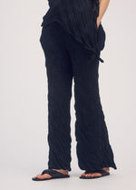 A model wears the ISSEY MIYAKE WRINKLED AND TWISTED trousers.
