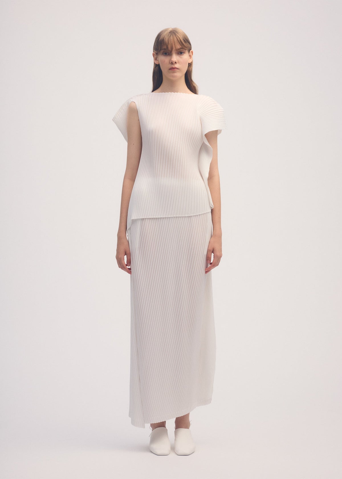 A model wears the ISSEY MIYAKE SHADOW STUDY PLEATS SOLID skirt.