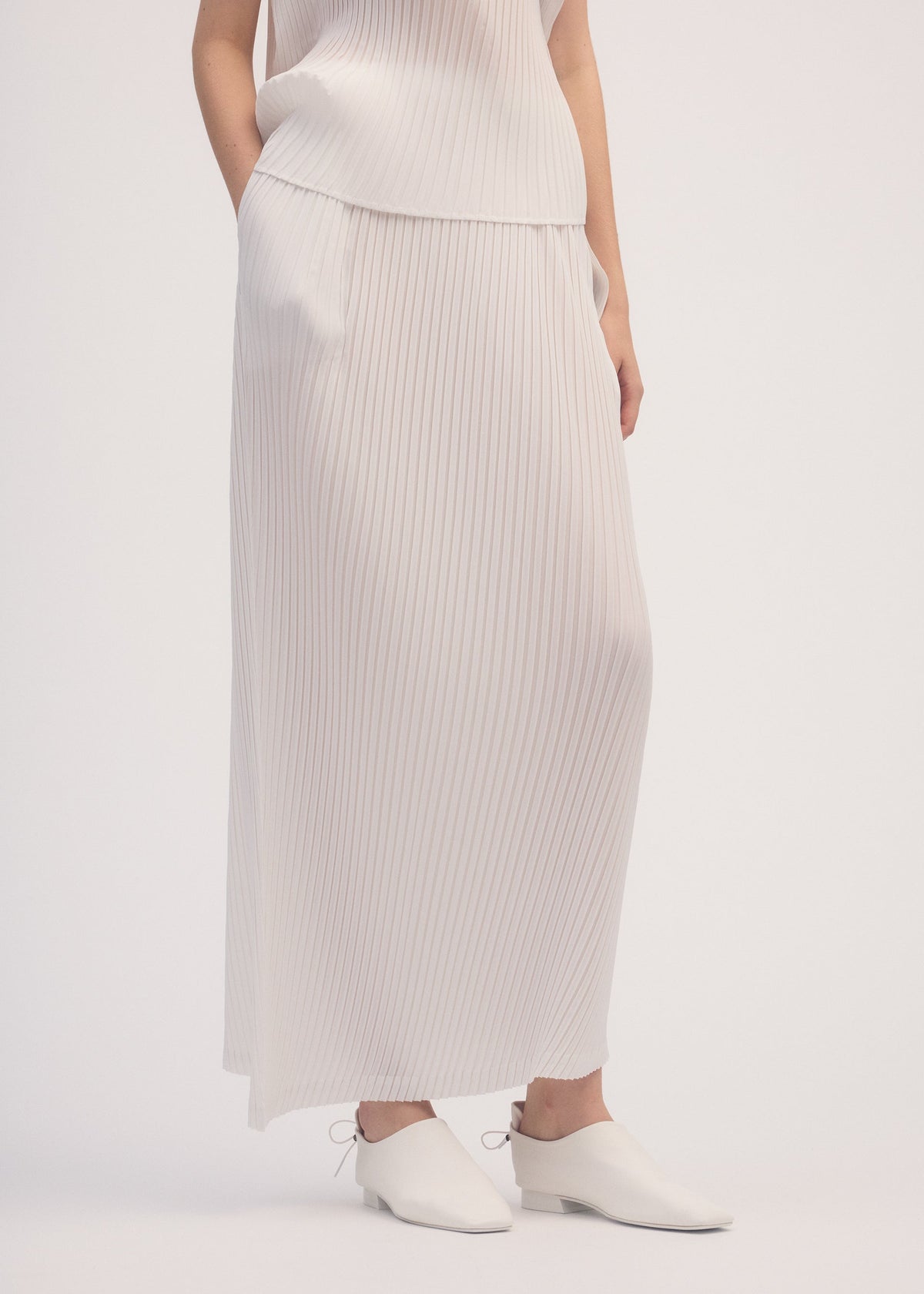 A model wears the ISSEY MIYAKE SHADOW STUDY PLEATS SOLID skirt.