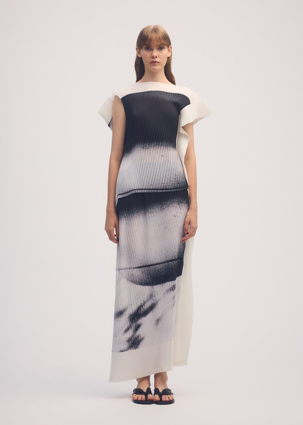 A model wears the ISSEY MIYAKE SHADOW STUDY PLEATS skirt.