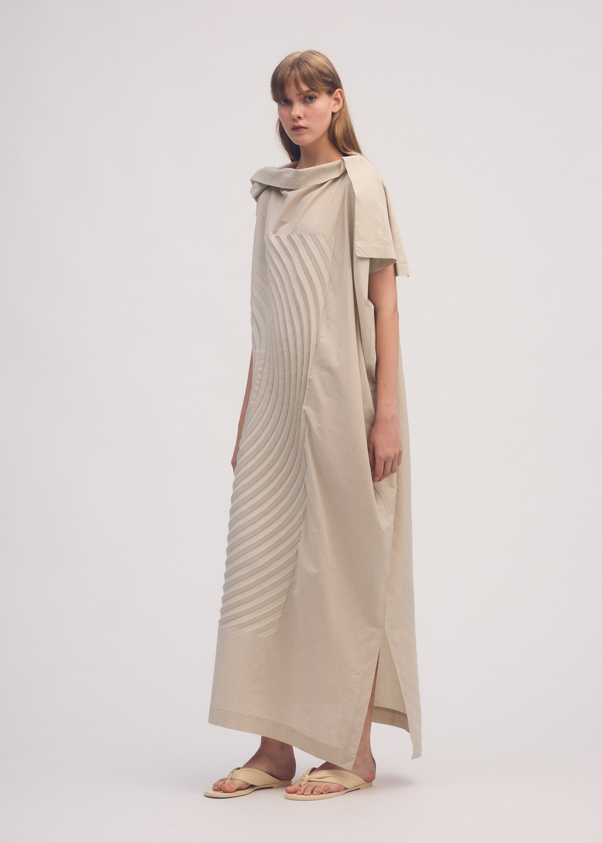 A model wears the ISSEY MIYAKE FLOW dress.