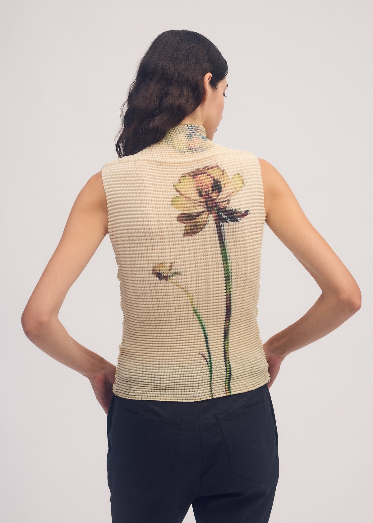 A model wears the ISSEY MIYAKE PRESSED FLORA PLEATS TOP shirt.