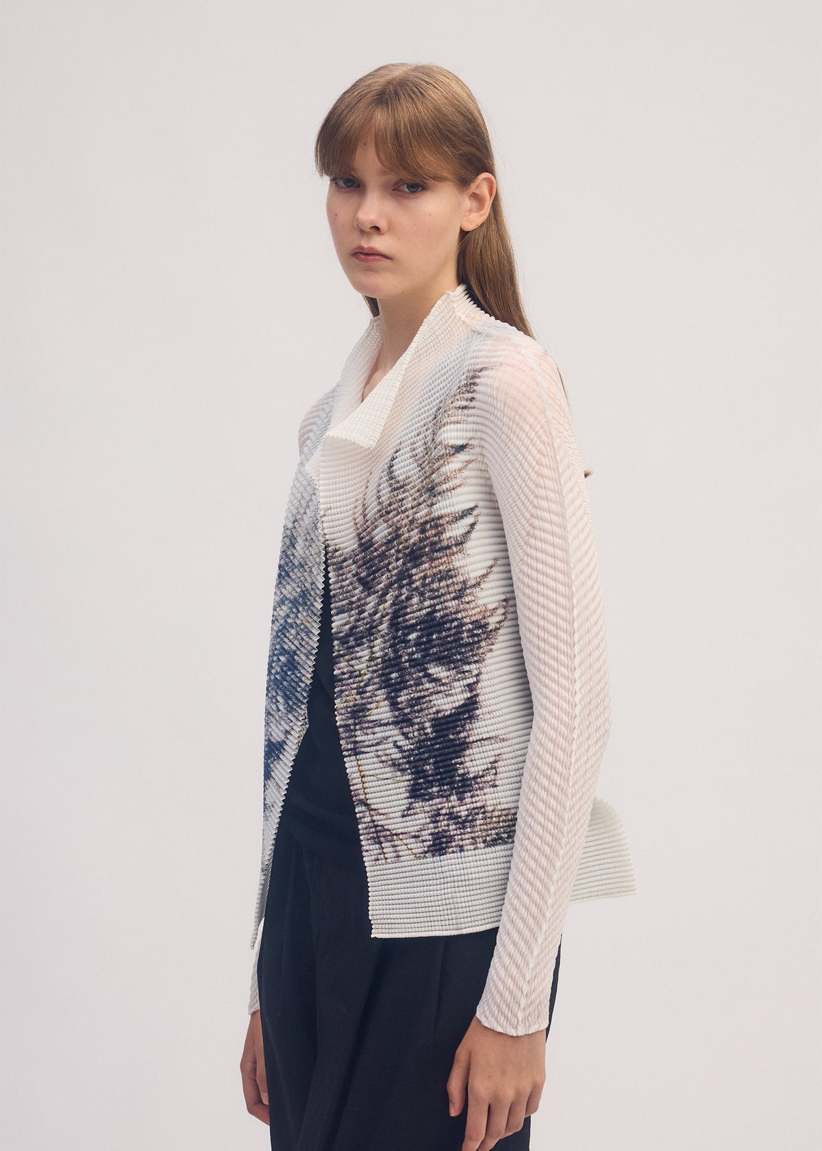 A model wears the ISSEY MIYAKE PRESSED FLORA PLEATS TOP shirt.