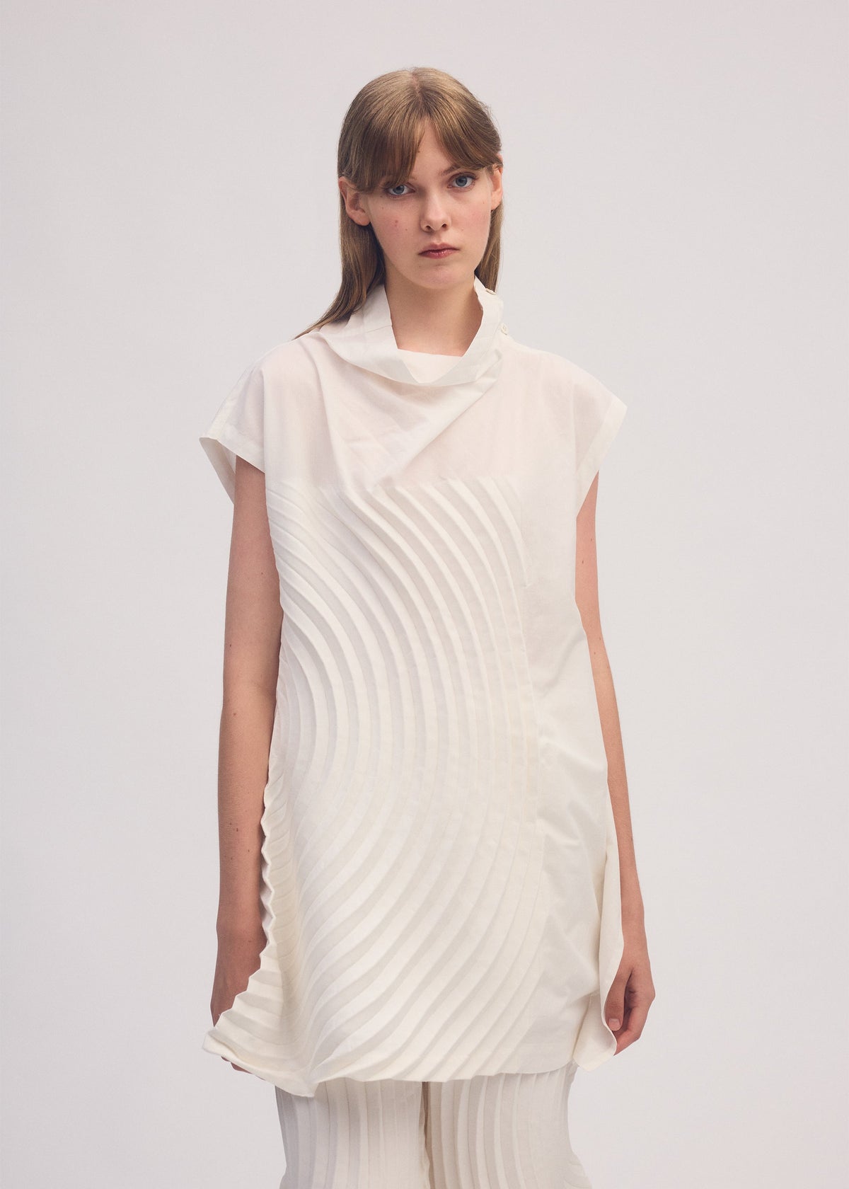 A model wears the ISSEY MIYAKE FLOW shirt.