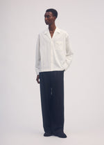 A model wears the ISSEY MIYAKE SIMPLE ENSEMBLE trousers.