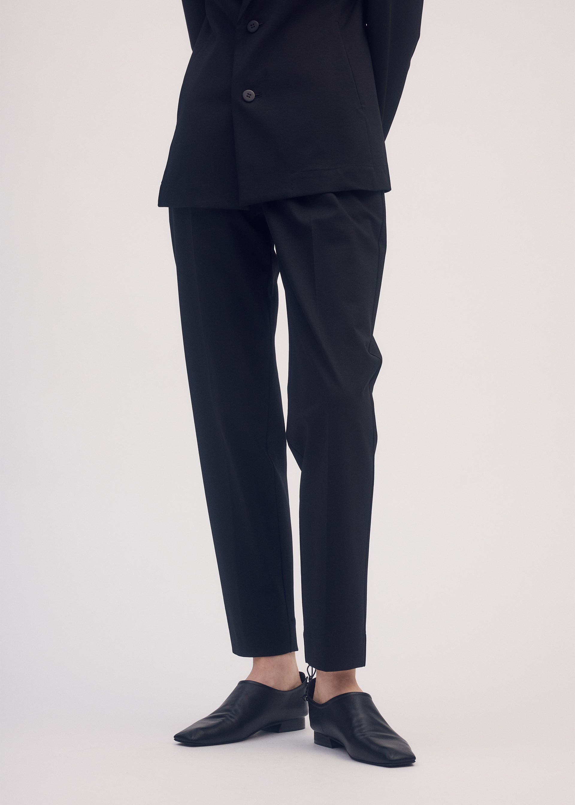 A model wears the ISSEY MIYAKE SIMPLE ENSEMBLE trousers.