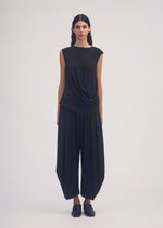 A model wears the ISSEY MIYAKE DRAPE JERSEY 56 trousers.