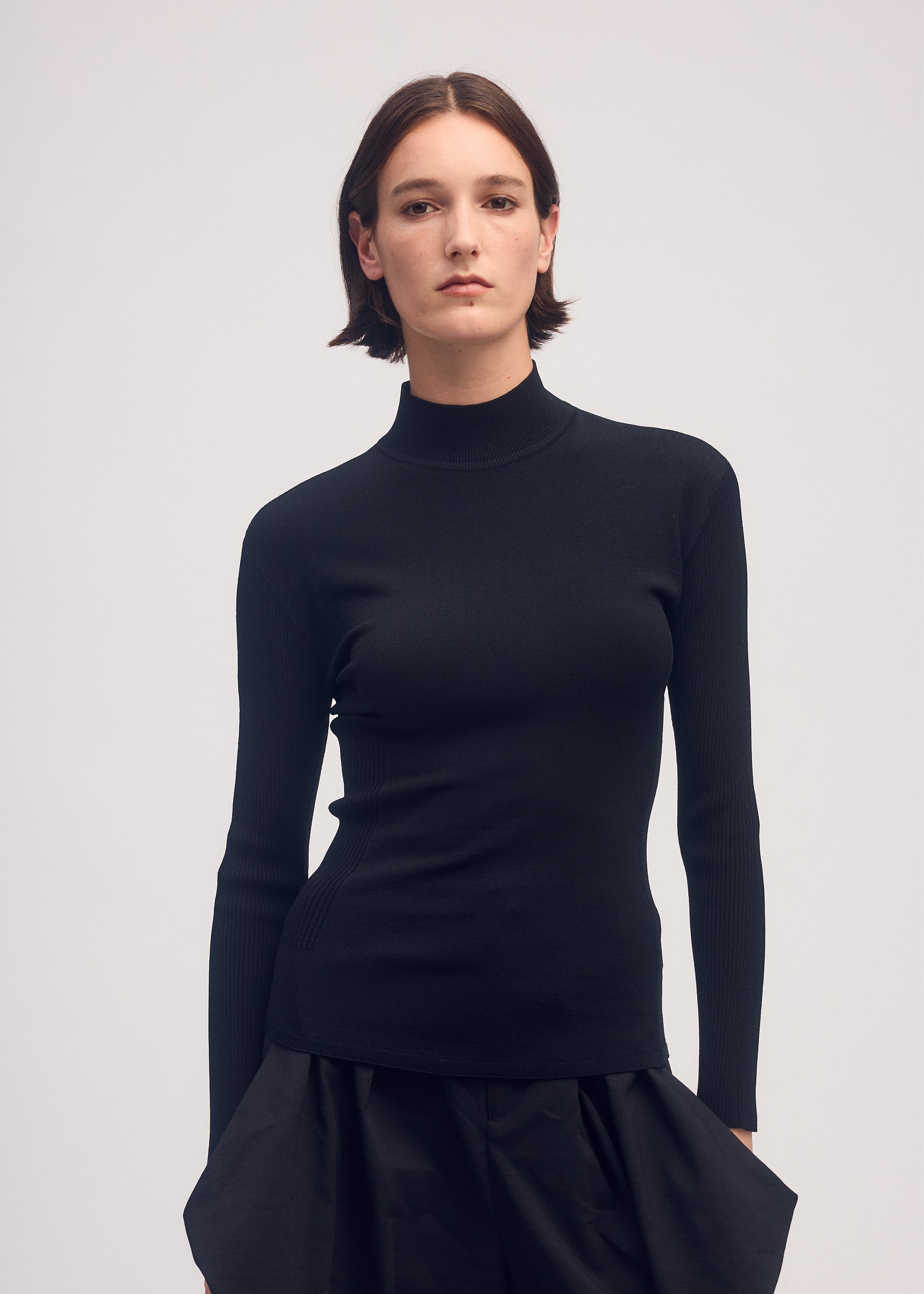 A model wears the ISSEY MIYAKE MELLOW STRETCH top.