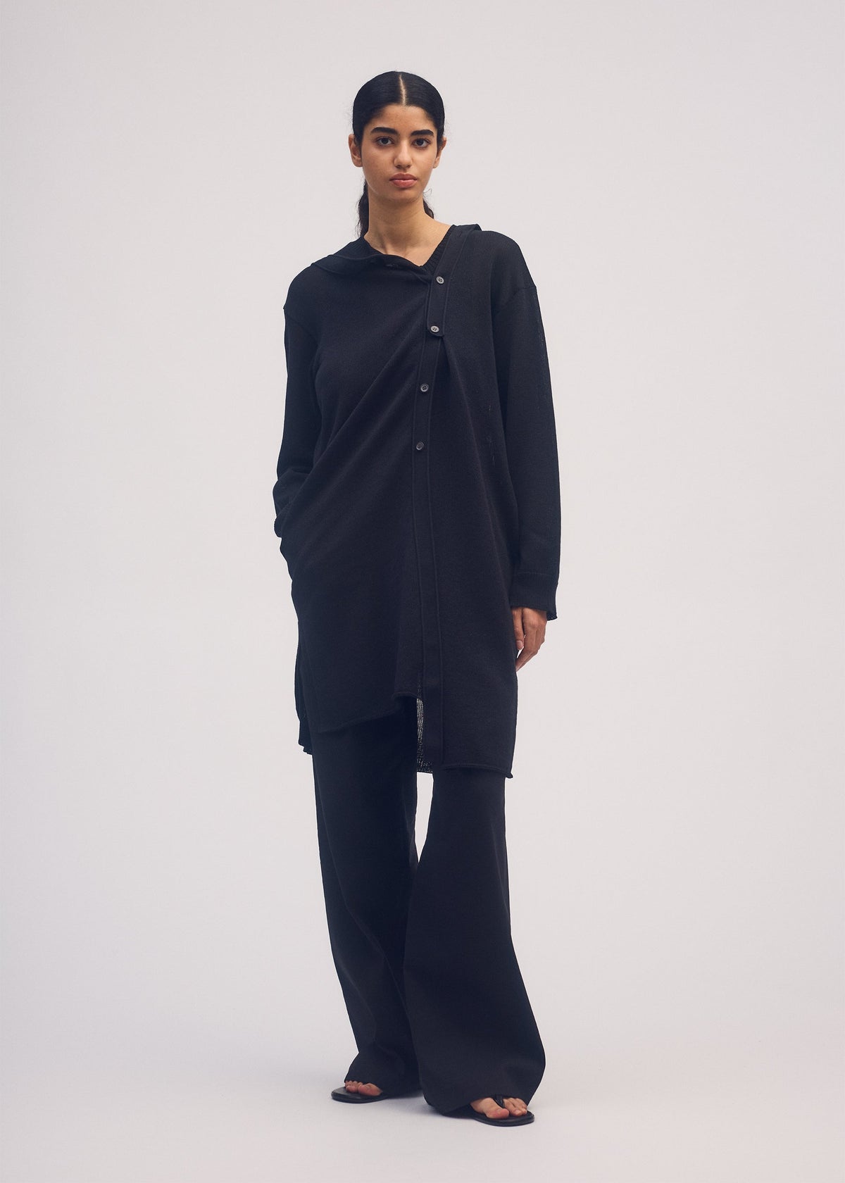 A model wears the ISSEY MIYAKE BUTTONED DRAPE KNIT cardigan.