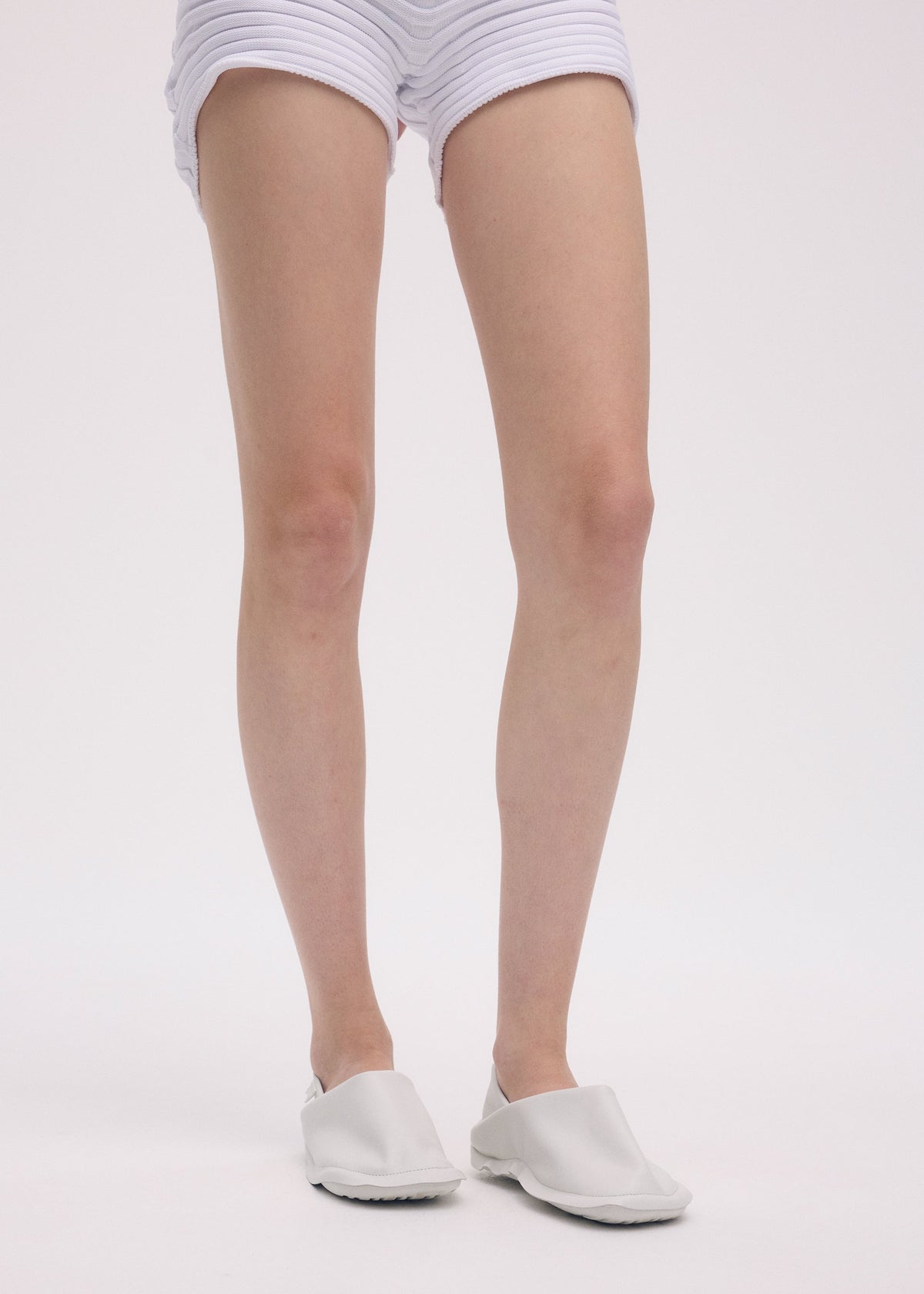 A model wears the ISSEY MIYAKE PEU FORM shoes.