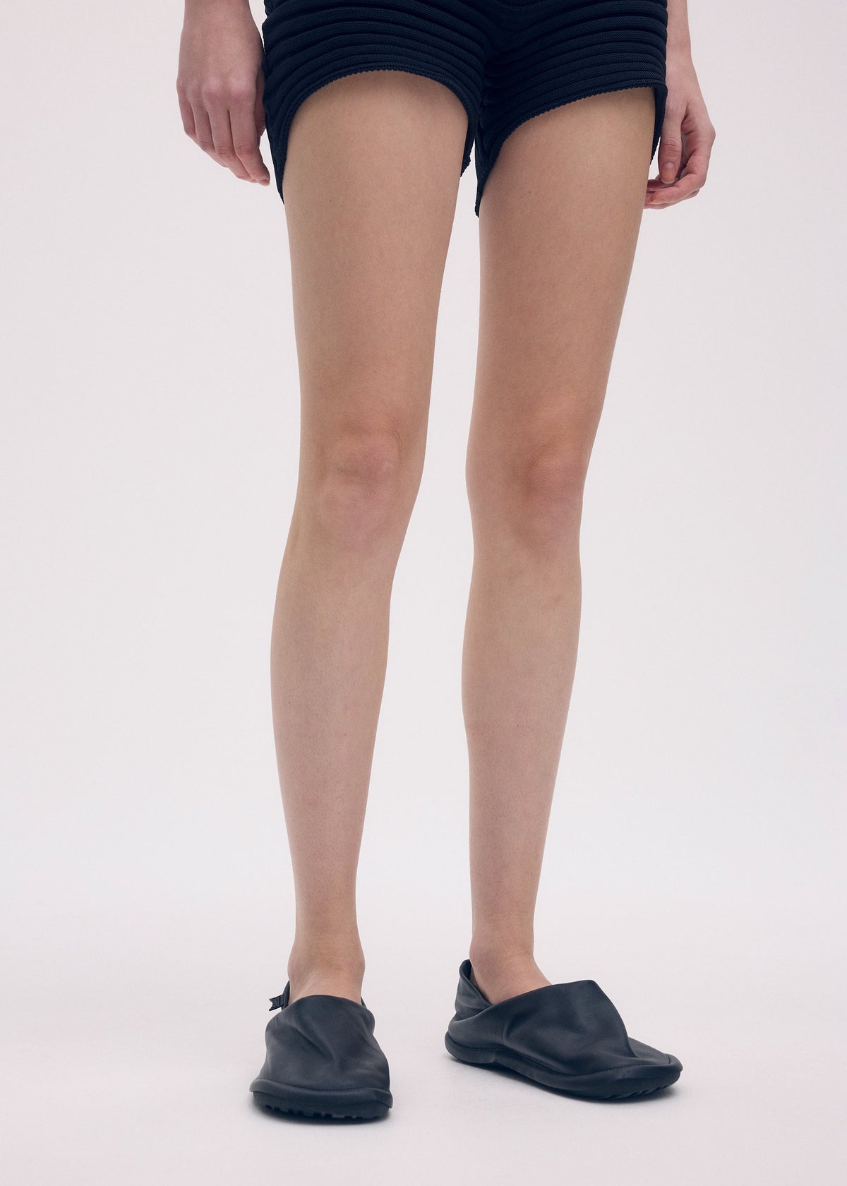 A model wears the ISSEY MIYAKE PEU FORM shoes.