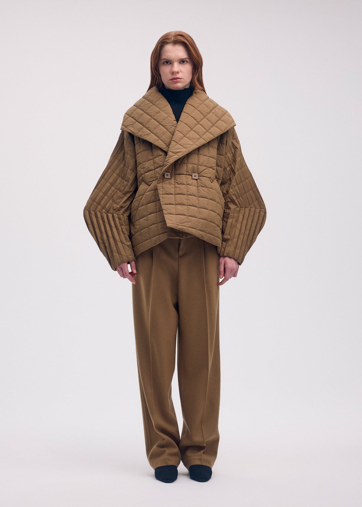 A model wears the ISSEY MIYAKE PLEATED GRID coat.