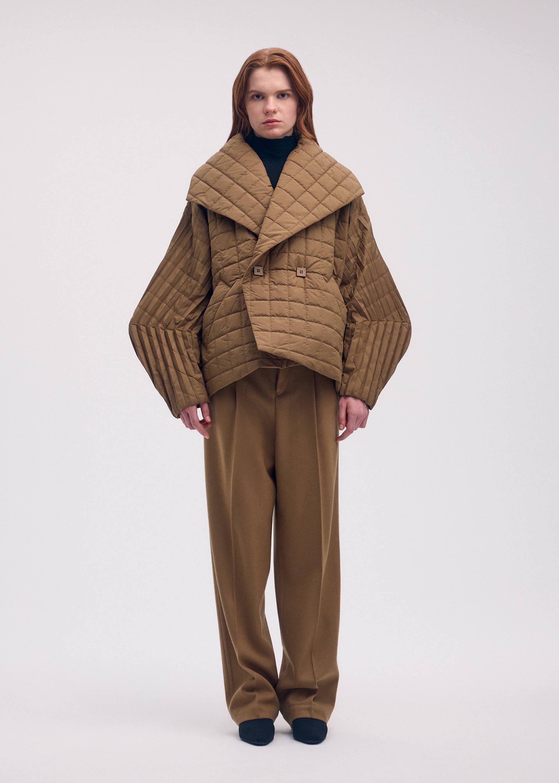 A model wears the ISSEY MIYAKE PLEATED GRID coat.