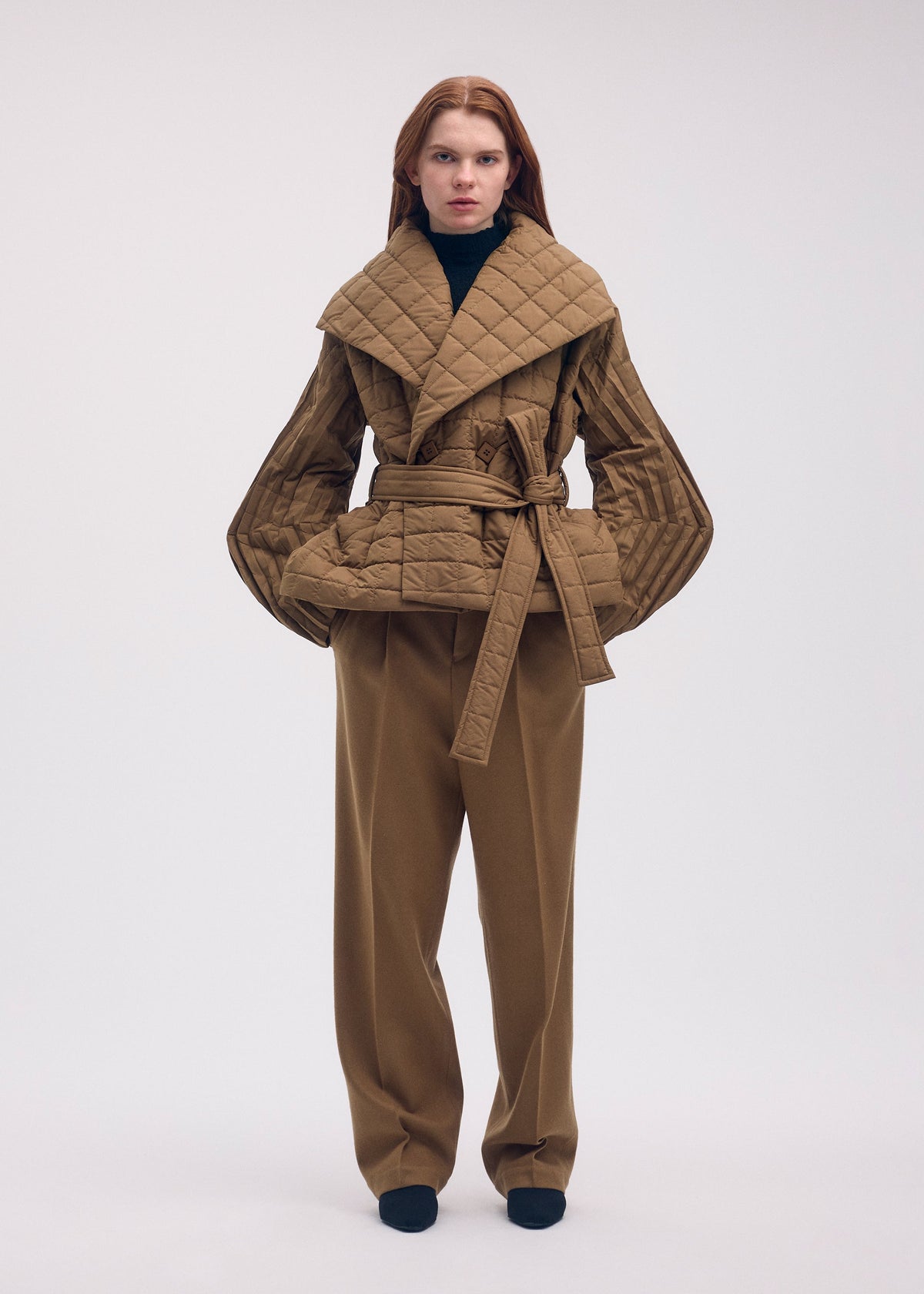 A model wears the ISSEY MIYAKE PLEATED GRID coat.